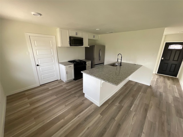 kitchen featuring dark wood-style flooring, a sink, white cabinetry, baseboards, and black appliances