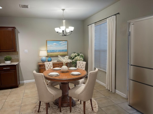 dining area featuring an inviting chandelier, light tile patterned flooring, visible vents, and baseboards