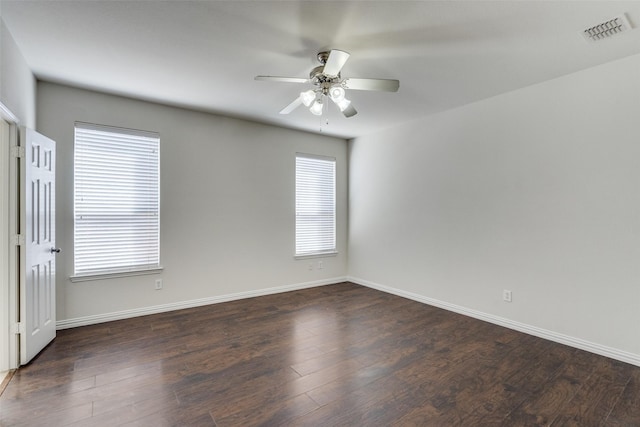 empty room featuring dark wood-style floors, visible vents, baseboards, and ceiling fan