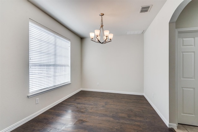 spare room featuring wood finished floors, visible vents, baseboards, arched walkways, and a chandelier