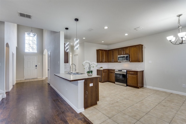 kitchen with arched walkways, a notable chandelier, stainless steel appliances, and a sink