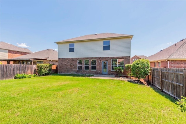 rear view of house featuring a yard, brick siding, and a fenced backyard