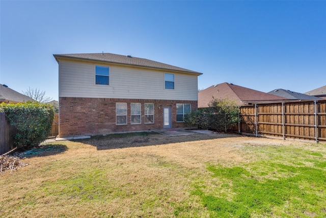 back of house with a yard, a fenced backyard, and brick siding