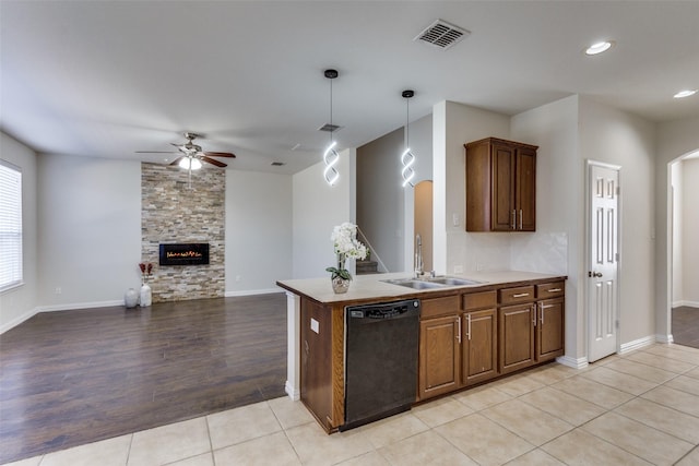 kitchen featuring visible vents, arched walkways, a sink, a stone fireplace, and dishwasher