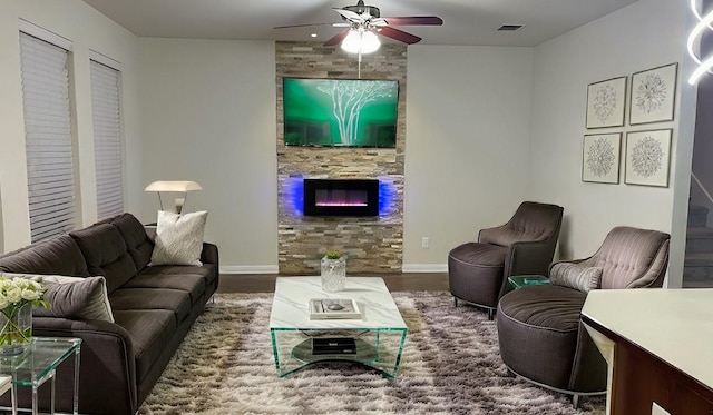 living room with visible vents, a ceiling fan, wood finished floors, a large fireplace, and baseboards