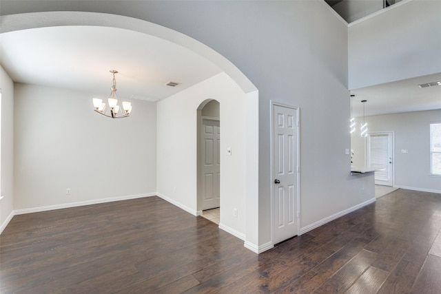 unfurnished room featuring dark wood finished floors, visible vents, a notable chandelier, and baseboards