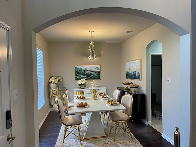 dining area featuring visible vents, baseboards, arched walkways, and dark wood-style flooring