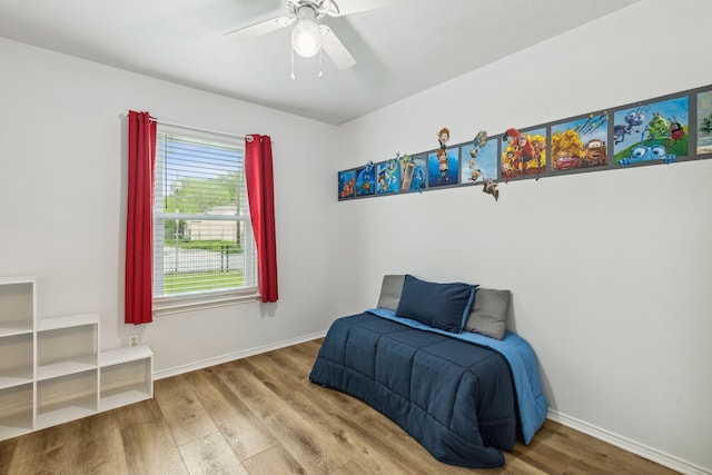 bedroom featuring a ceiling fan, baseboards, and wood finished floors