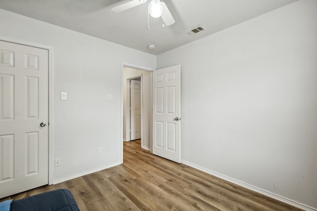 unfurnished bedroom featuring a ceiling fan, wood finished floors, visible vents, and baseboards