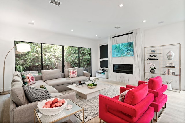 living room with light wood finished floors, a premium fireplace, visible vents, and recessed lighting