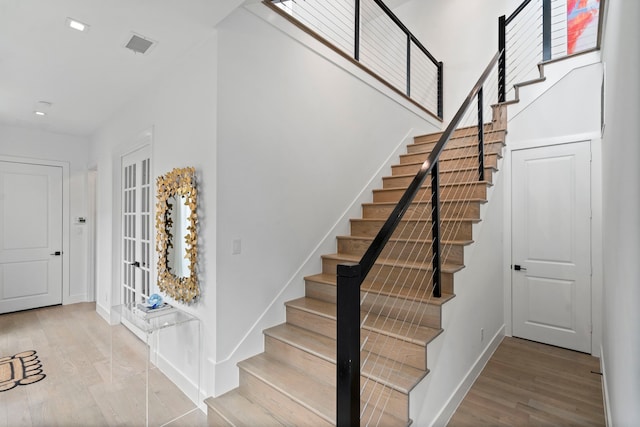 staircase featuring visible vents, baseboards, wood finished floors, and recessed lighting