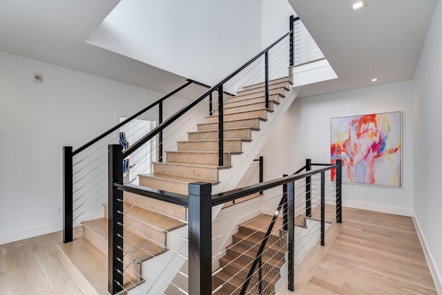 staircase with baseboards, wood finished floors, and recessed lighting