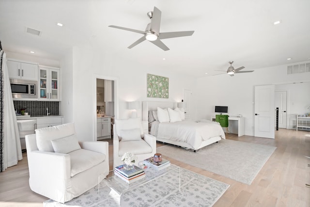 bedroom with light wood-style flooring, visible vents, a sink, and recessed lighting