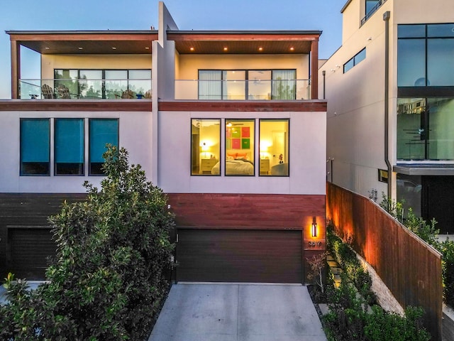 exterior space with concrete driveway, a balcony, an attached garage, and stucco siding