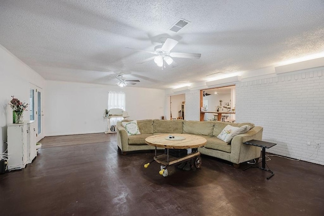 living area with a ceiling fan, visible vents, brick wall, finished concrete floors, and a textured ceiling