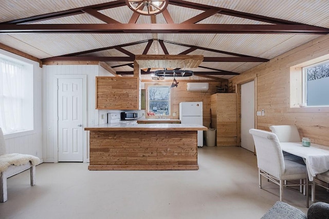 kitchen with freestanding refrigerator, concrete floors, a peninsula, light countertops, and vaulted ceiling