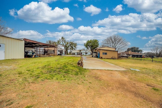 view of yard with an outbuilding, fence, and driveway