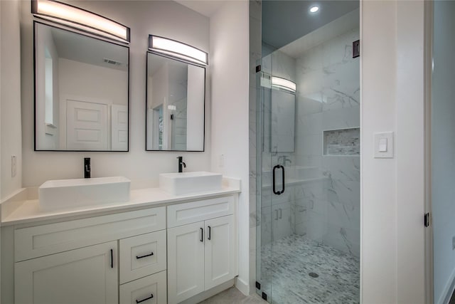 bathroom featuring double vanity, a marble finish shower, visible vents, and a sink