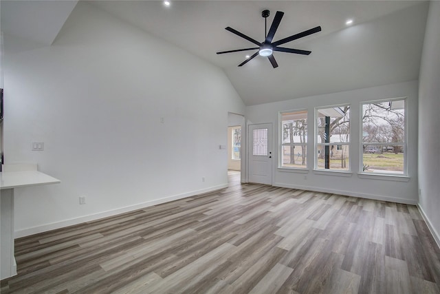 unfurnished living room featuring ceiling fan, high vaulted ceiling, recessed lighting, wood finished floors, and baseboards