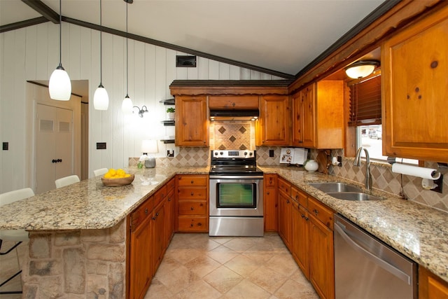 kitchen with brown cabinets, a sink, under cabinet range hood, appliances with stainless steel finishes, and vaulted ceiling