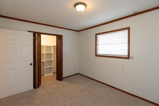 unfurnished bedroom featuring a closet, light carpet, baseboards, and ornamental molding