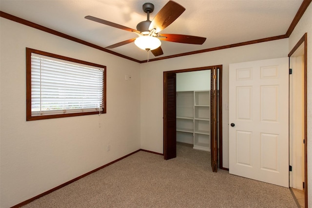 unfurnished bedroom featuring a ceiling fan, a closet, crown molding, baseboards, and light colored carpet