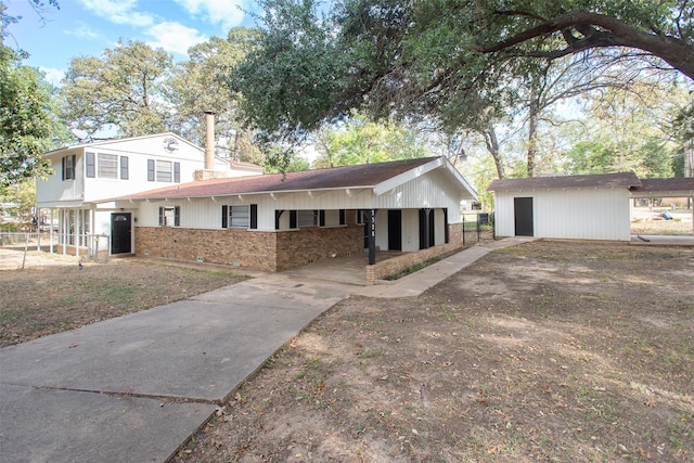 view of front of home with an outbuilding, fence, concrete driveway, a carport, and brick siding