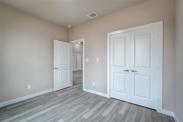 unfurnished bedroom featuring light wood-style floors, a closet, visible vents, and baseboards