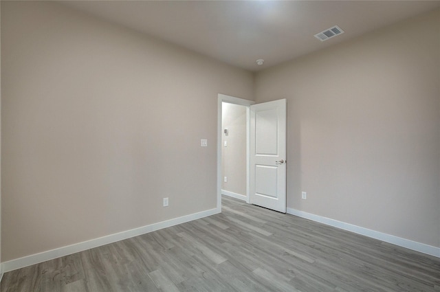 spare room with wood finished floors, visible vents, and baseboards