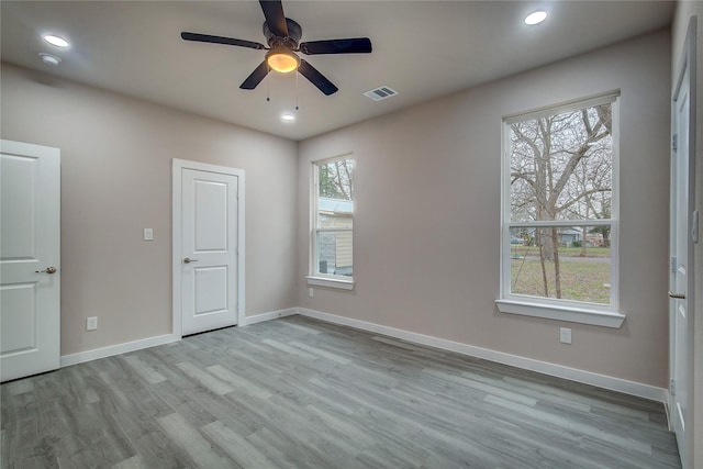 empty room featuring baseboards, visible vents, wood finished floors, and recessed lighting