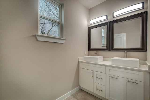 bathroom with double vanity, tile patterned flooring, baseboards, and a sink