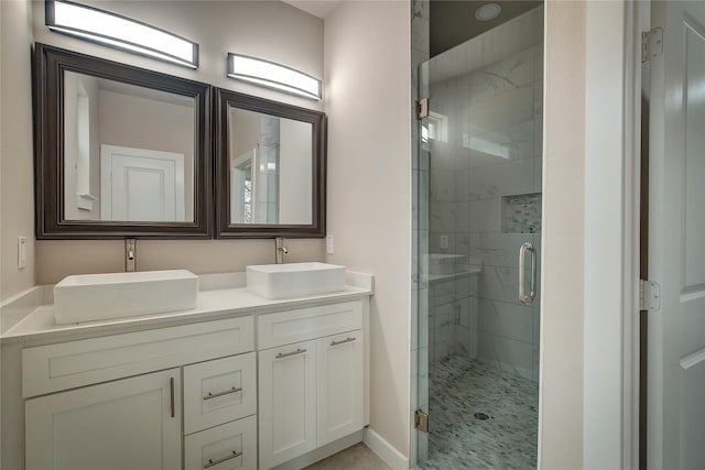 full bathroom with a stall shower, a sink, baseboards, and double vanity