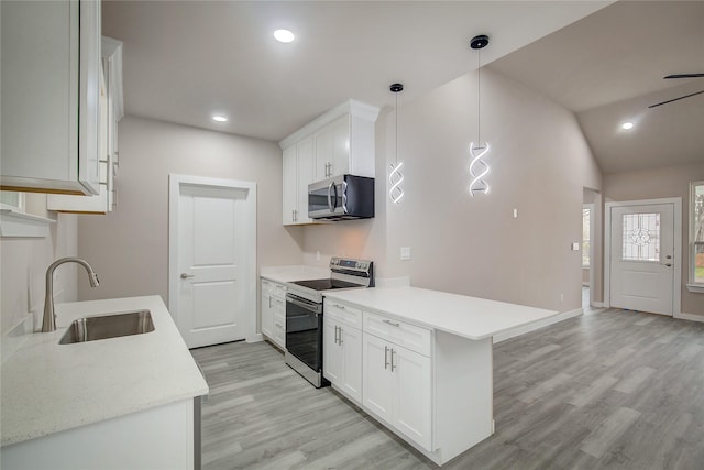 kitchen featuring a peninsula, a sink, light wood-style floors, light countertops, and appliances with stainless steel finishes