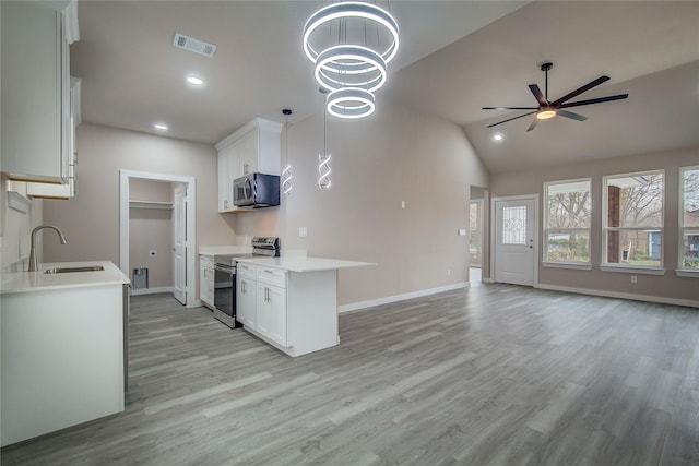 kitchen featuring light wood-style flooring, stainless steel appliances, a sink, visible vents, and open floor plan