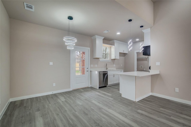 kitchen with light wood-style floors, white cabinets, light countertops, stainless steel dishwasher, and baseboards