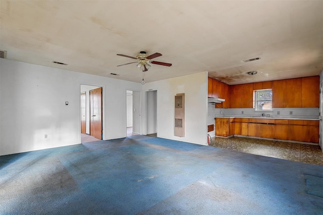 kitchen featuring under cabinet range hood, visible vents, open floor plan, light countertops, and brown cabinets