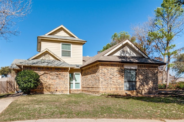 traditional home featuring a front yard, brick siding, and fence