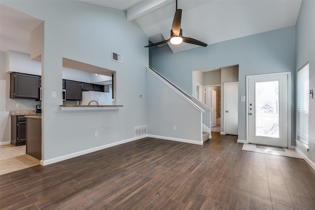 unfurnished living room featuring baseboards, visible vents, wood finished floors, and beamed ceiling