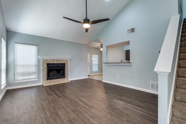 unfurnished living room featuring dark wood-style floors, a fireplace with flush hearth, stairs, and visible vents