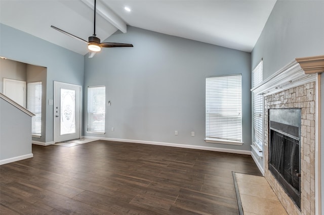 unfurnished living room with baseboards, beamed ceiling, a tiled fireplace, and wood finished floors