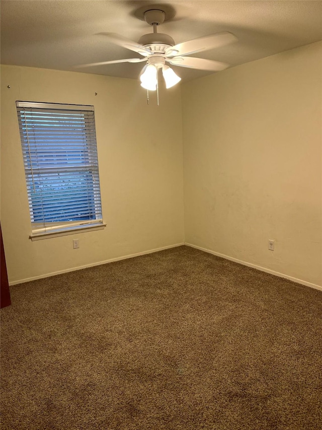 unfurnished room featuring ceiling fan, a textured ceiling, dark carpet, and baseboards