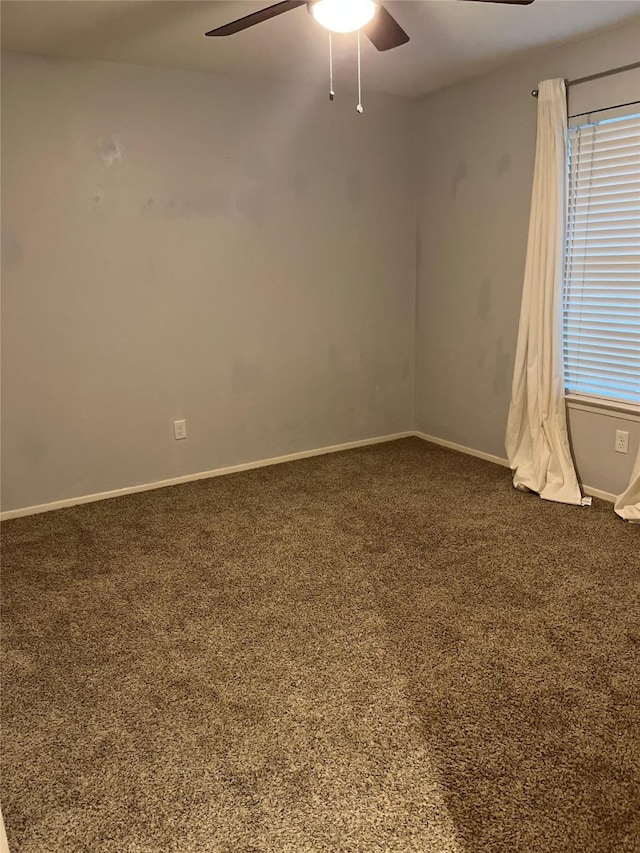 carpeted empty room with ceiling fan and baseboards