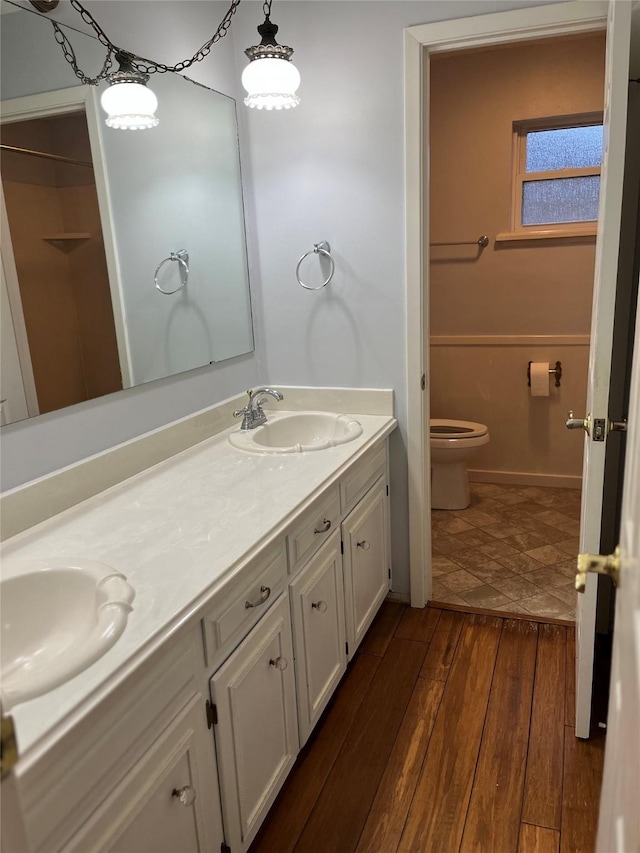 bathroom featuring toilet, hardwood / wood-style floors, double vanity, and a sink