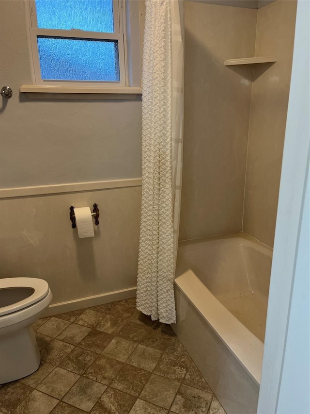 bathroom with toilet, baseboards, and shower / tub combo with curtain