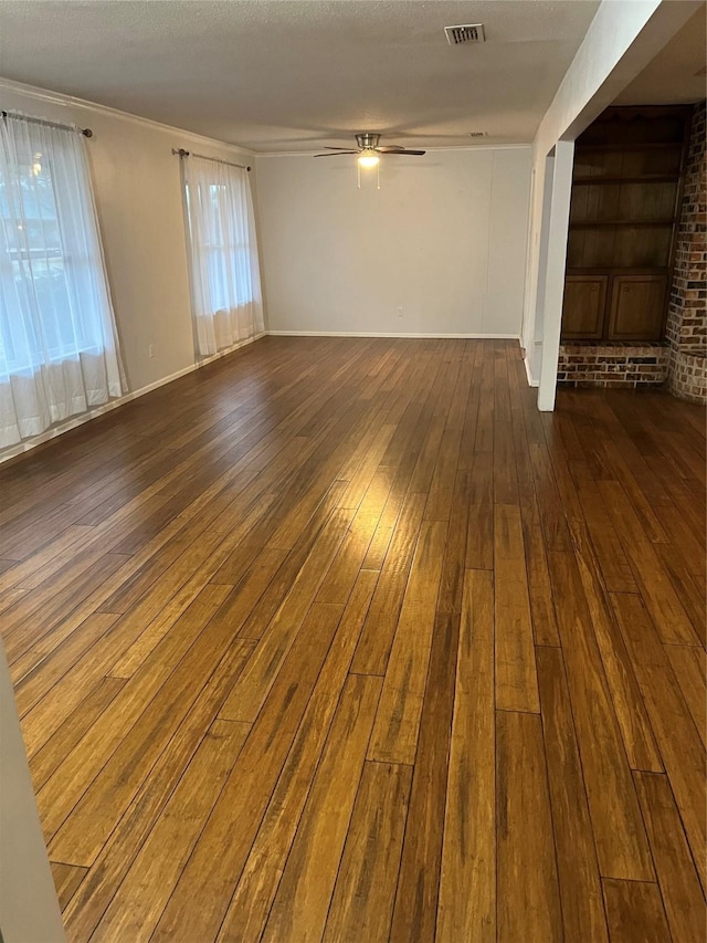 unfurnished living room with visible vents, a wealth of natural light, hardwood / wood-style flooring, and a ceiling fan