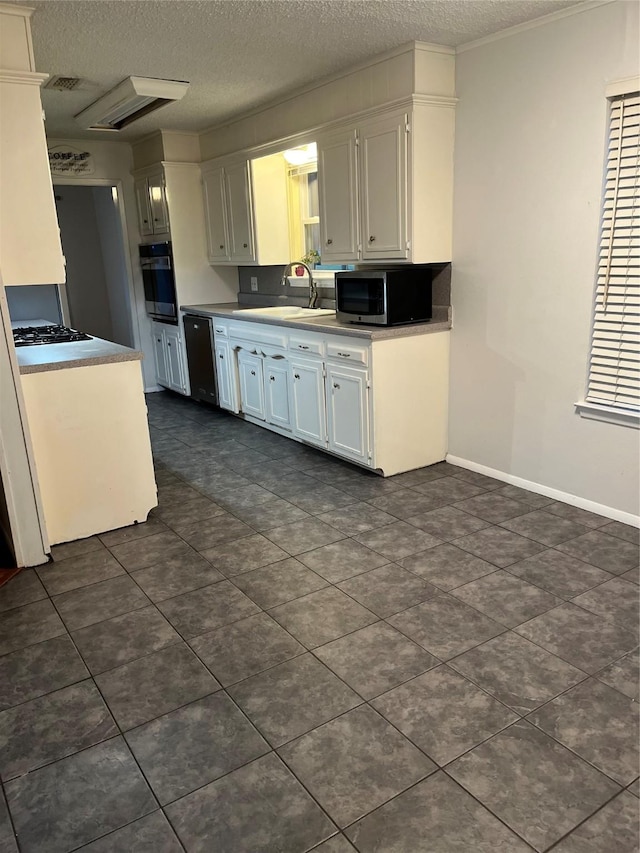 kitchen featuring stainless steel microwave, a sink, a textured ceiling, oven, and dishwashing machine