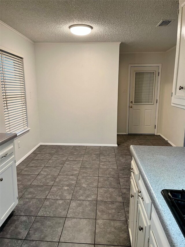 kitchen with black gas cooktop, visible vents, white cabinets, dark tile patterned flooring, and baseboards