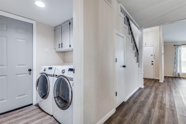 washroom with wood finished floors, cabinet space, baseboards, and separate washer and dryer