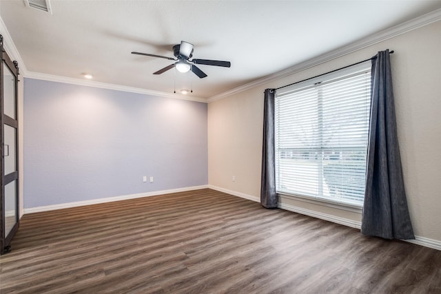 spare room with a barn door, visible vents, crown molding, and wood finished floors