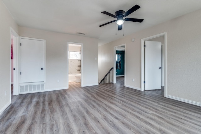 interior space featuring connected bathroom, wood finished floors, visible vents, and baseboards